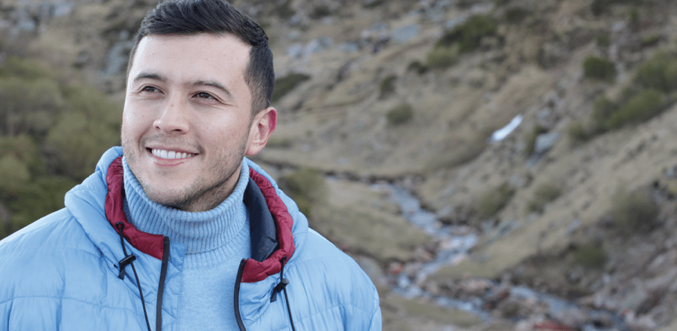 Man smiling outside on a hike.