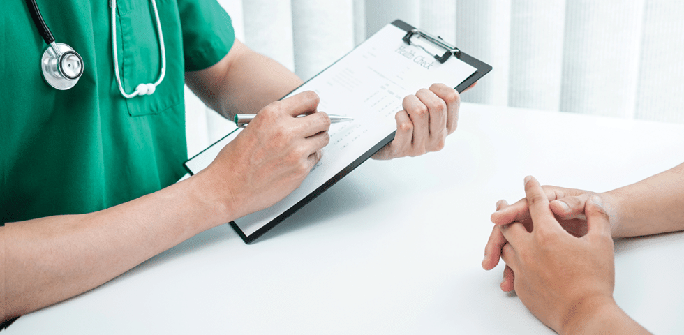 Doctor holding clipboard across from a patient.