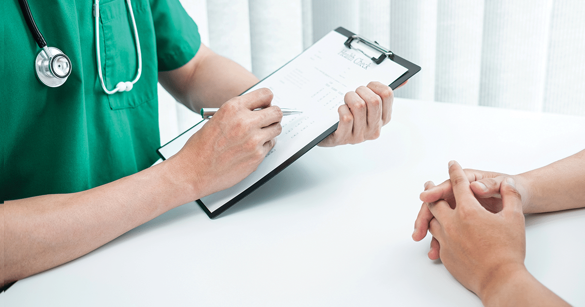 Doctor holding clipboard across from a patient.