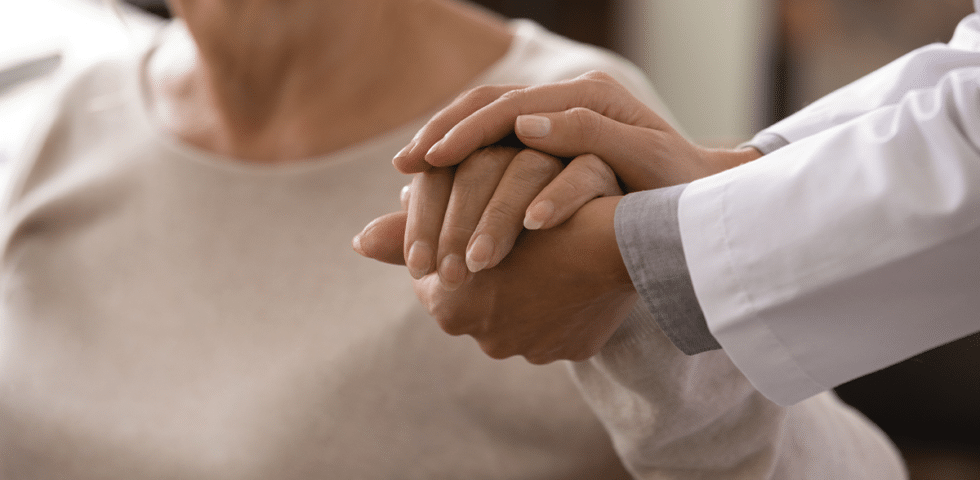 A doctor holding patient's hand.